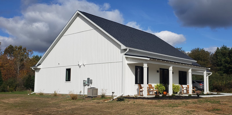 Modern white and black farmhouse with vertical siding. 